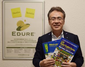 同社出版の英語教材を持つ山口社長